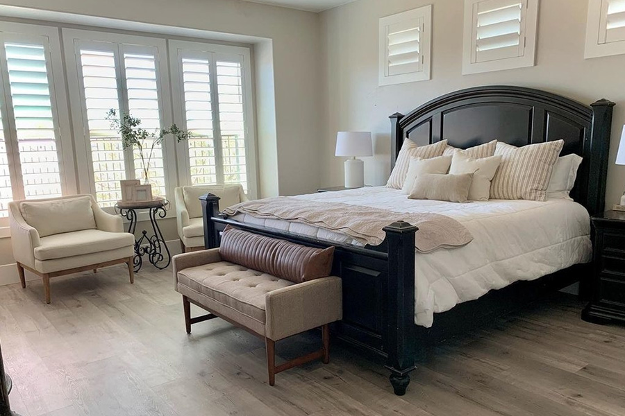 Stylish bedroom with elegant furniture and large windows covered by Polywood plantation shutters. 