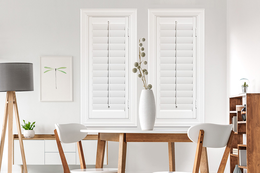 Sunburst's selection of stylish window treatments for designers in Denver makes it easy to find the perfect ones for every design job. White Polywood shutters on two windows in a modern Scandinavian-style room