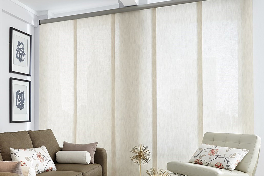Find window treatments to complete any interior design among our extensive selection at Sunburst Shutters Denver. Long off-white window shades on a tall window in a modern living room