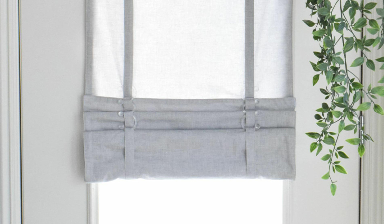 With a tiered tumble shade in Denver, you can block sun glare all year round. Gray rolled tumble shade on a glass door